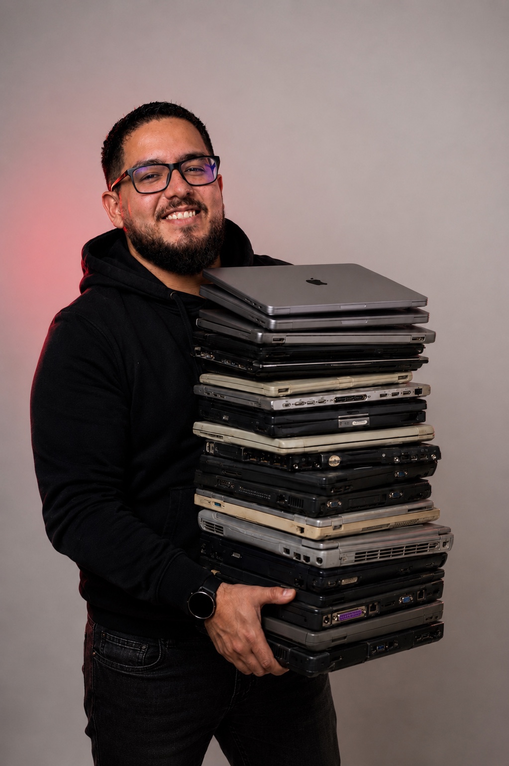 Rodrigo holding a stack of every laptop he has worked on